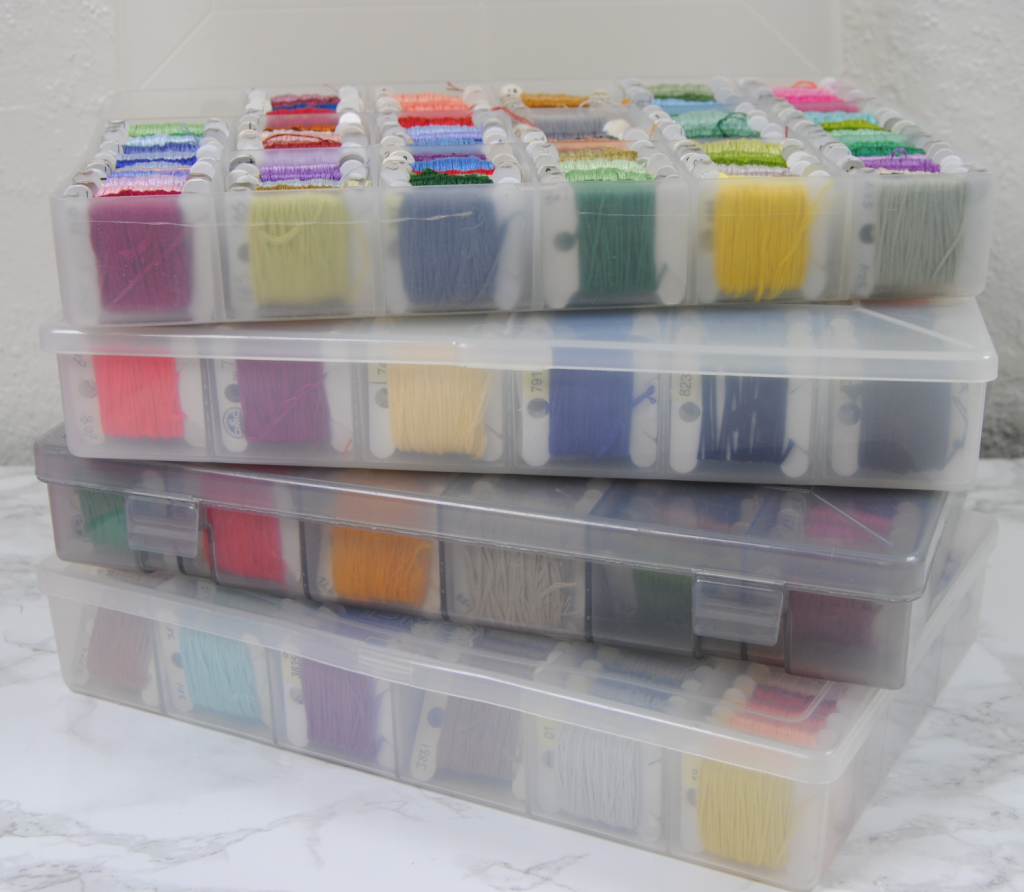A stack of four plastic thread boxes full of thread.