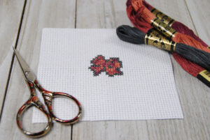 A finished cross stitch bow, with the materials used to create it.