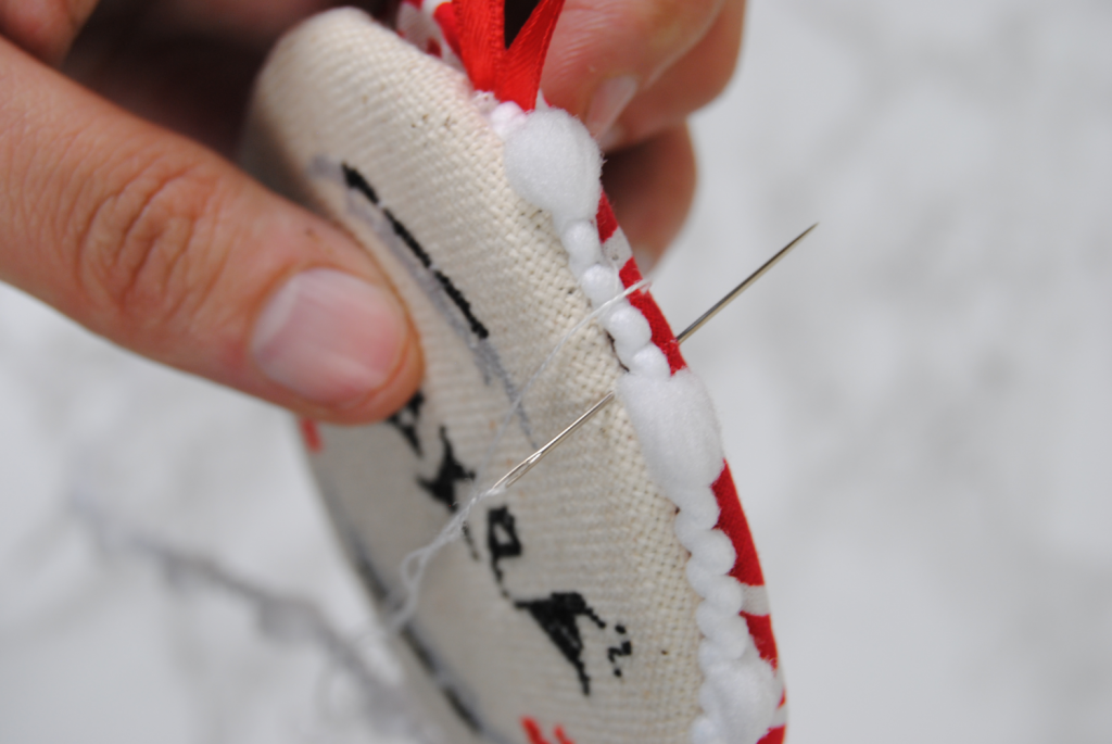 Demonstrating sewing together the fabric discs around a decorative ribbon