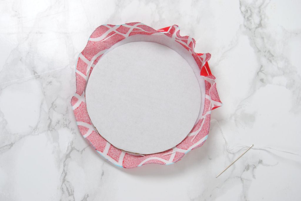 Running stitch fabric to cinch around cardboard.