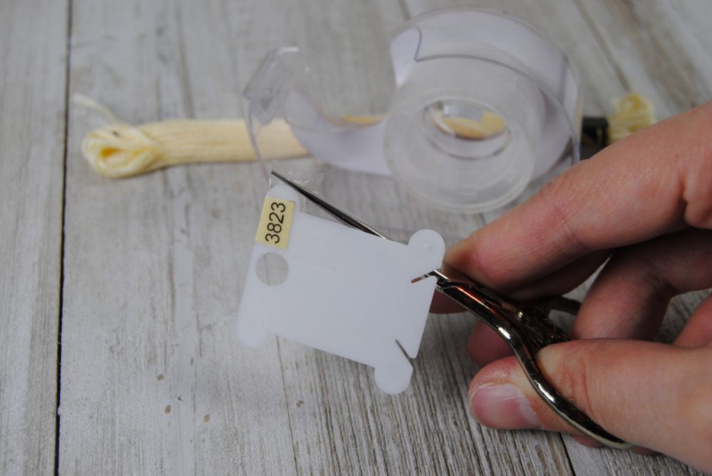 Trimming the excess tape off of a plastic thread bobbin