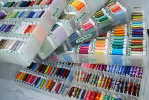 A stack of plastic bobbin boxes full of DMC embroidery thread