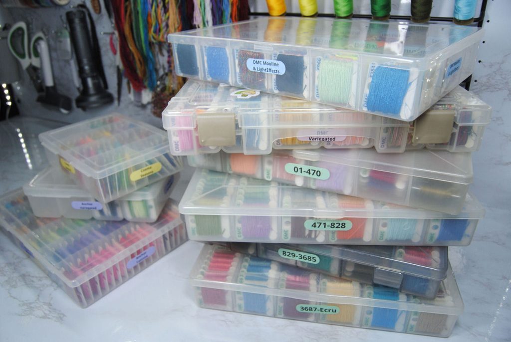 A stack of plastic thread boxes of all different brands and styles.