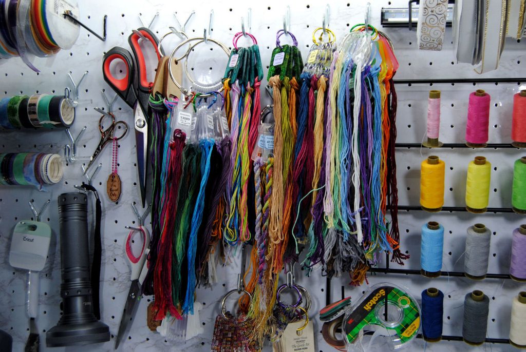 A pegboard holding embroidery thread on floss drops