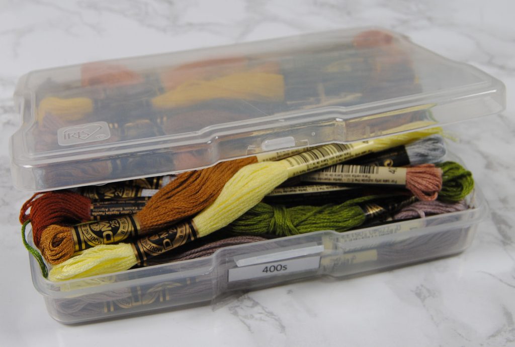 A plastic photo box full of embroidery skeins
