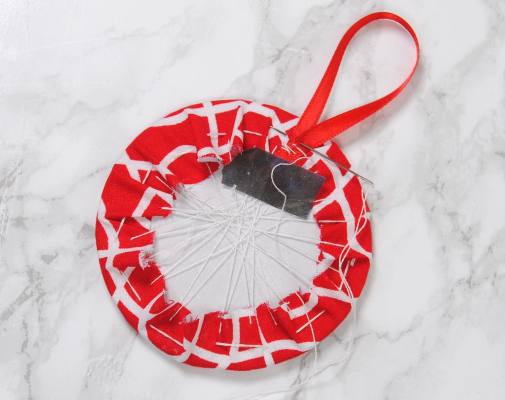 Sewing a ribbon loop to the inside of a fabric ornament.