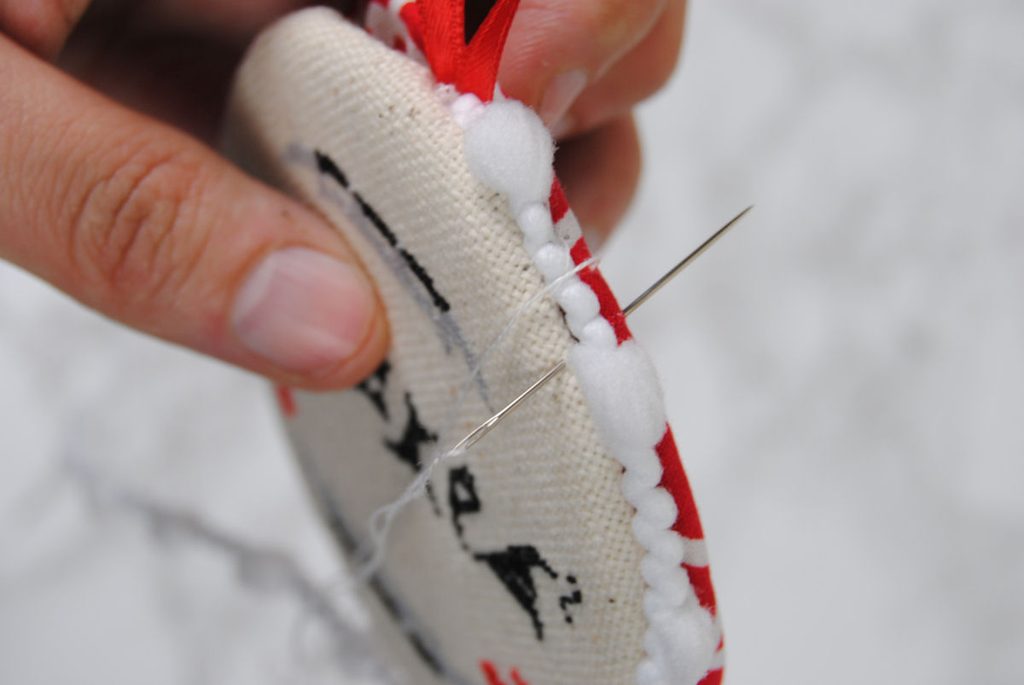 Close up of sewing pom pom cording on the edge of a round ornament