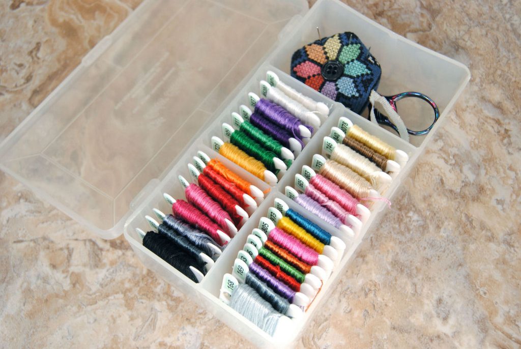 A small plastic box full of embroidery thread on bobbins