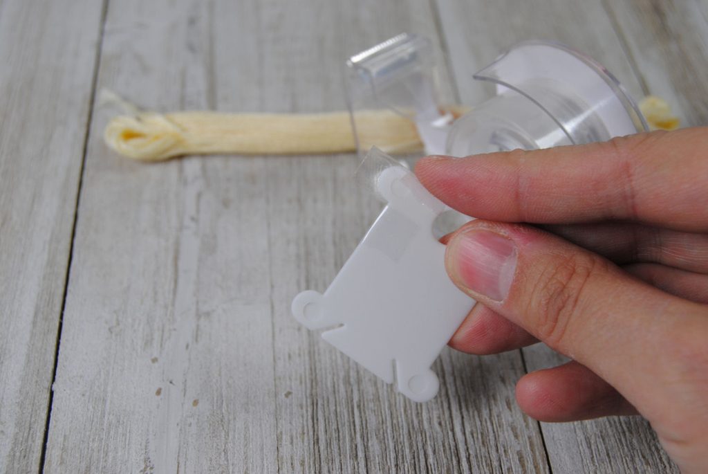 Wrapping clear tape around a plastic thread bobbin.