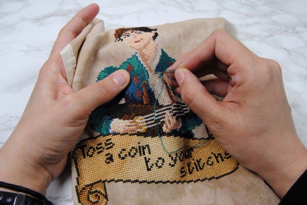 Demonstration of cross stitching in hand without a frame.