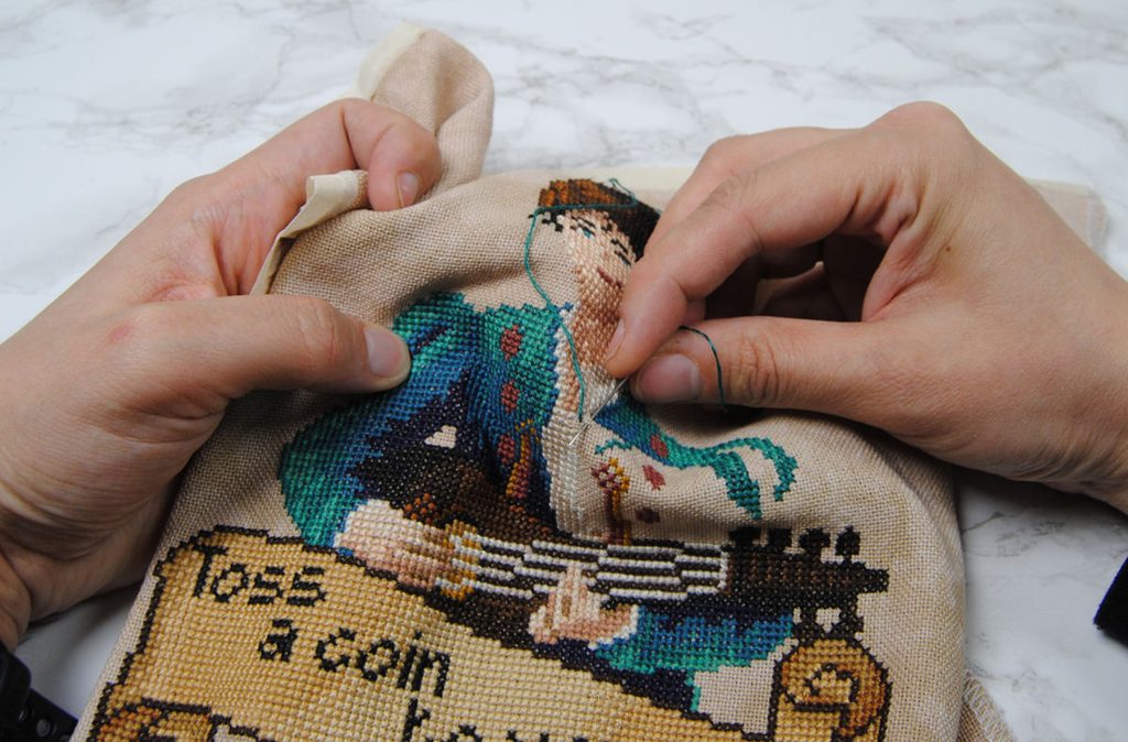 Demonstration of cross stitching in hand using the sewing method.