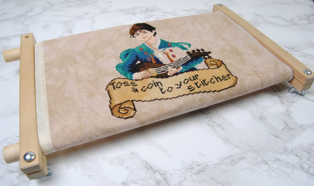 A cross stitch wip in a wooden scroll frame.
