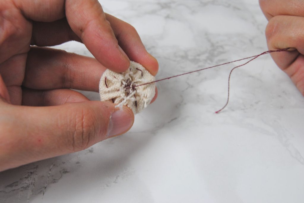 Demonstration of cinching fabric around a cardstock circle.