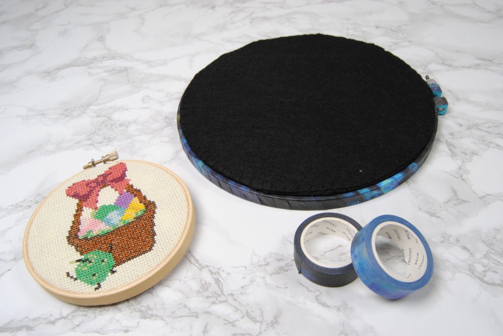 Two finished cross stitch hoops, one wrapped in washi tape with a felt back.