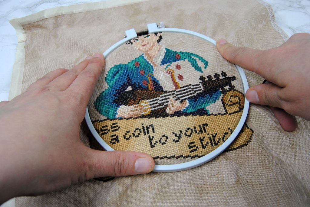 Demonstrating loading a cross stitch WIP into an embroidery hoop.