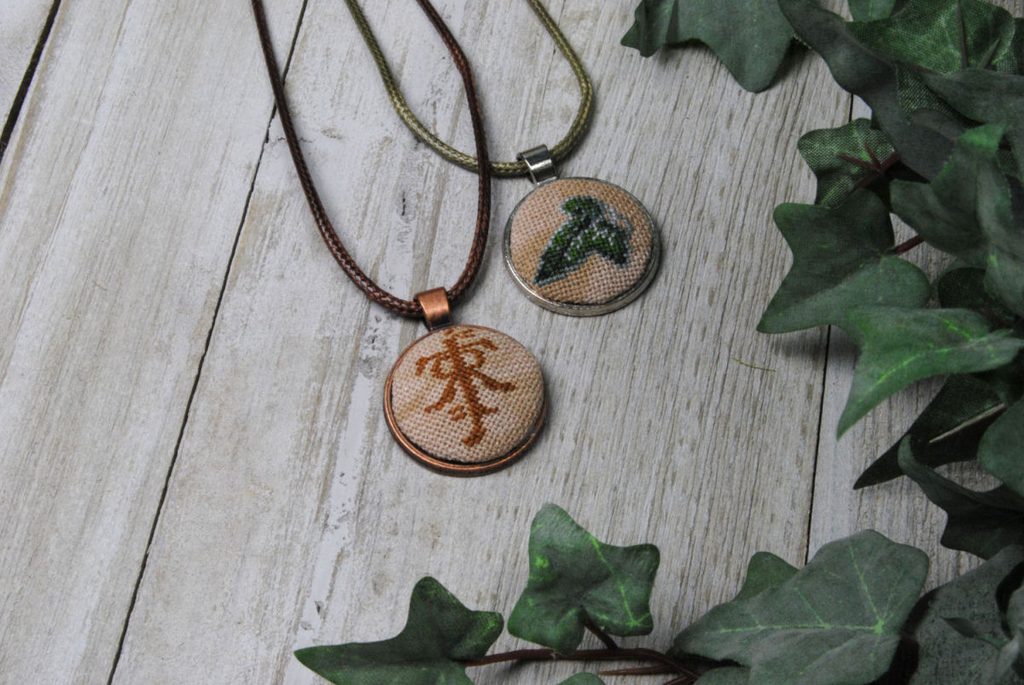 Two cross stitch pendant necklaces featuring motifs from Lord of the Rings