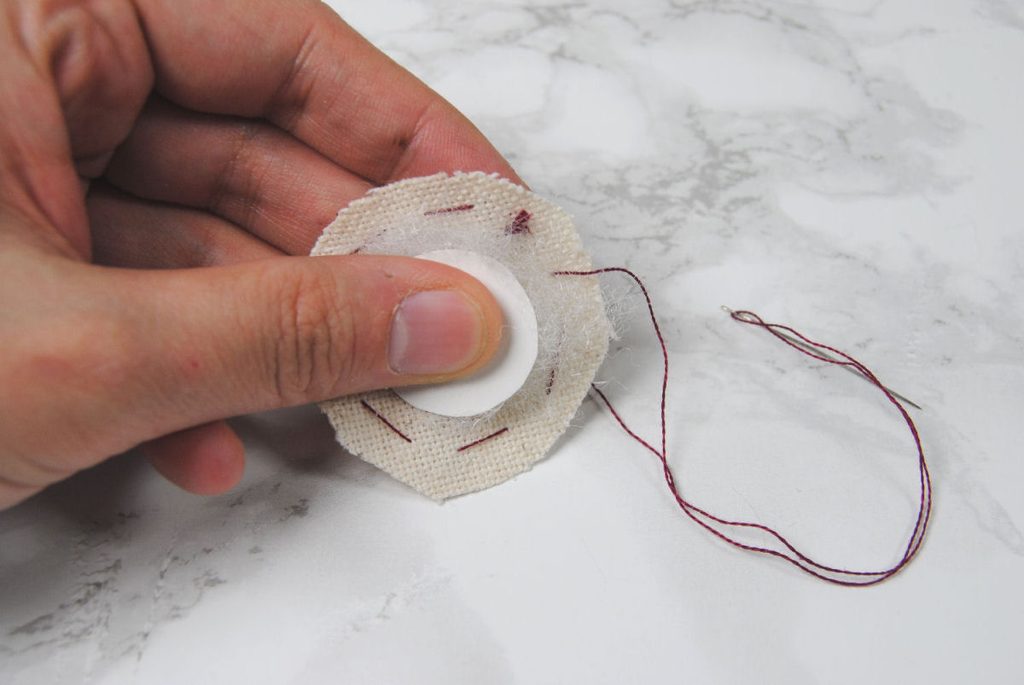 Demonstration of a running stitch around a circle of fabric.