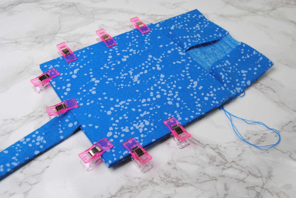 Sewing a fabric-covered square onto another using a ladder stitch along the edges.