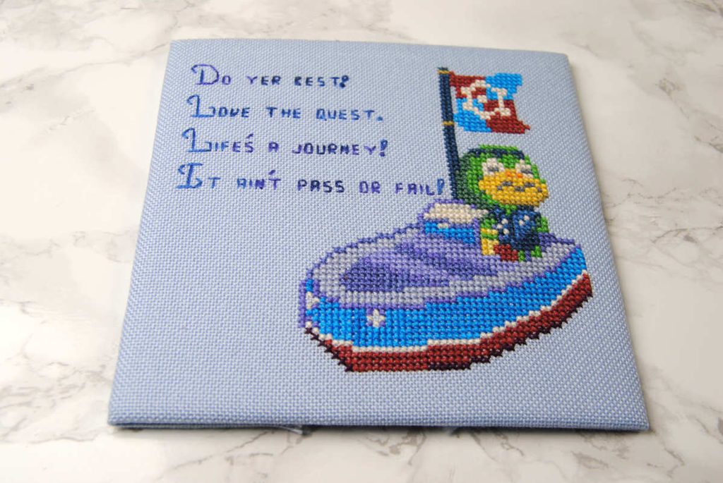 A cross stitch piece, sewn around a cardstock square.