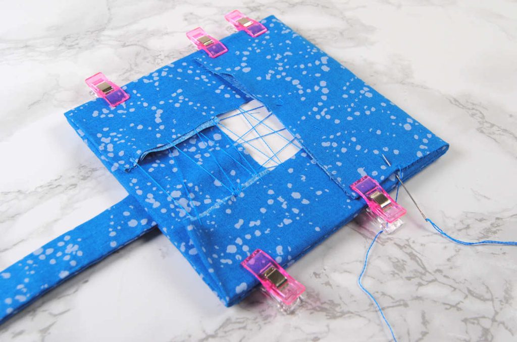 Sewing the upper flap onto the top square using a ladder stitch.