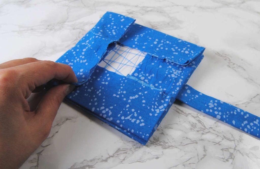 Folding the longer flap into the middle to secure it in place.