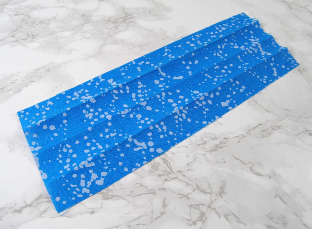 A long strip of fabric with crease lines dividing it into four long sections.