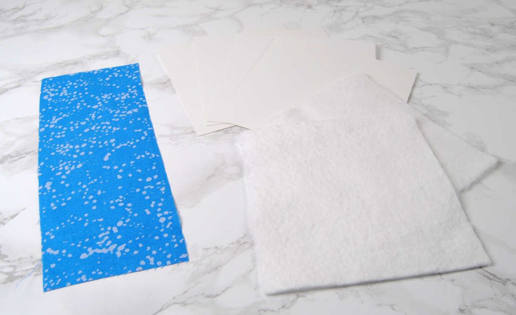 Materials for a flatfold finish - cardstock, batting, and fabric.
