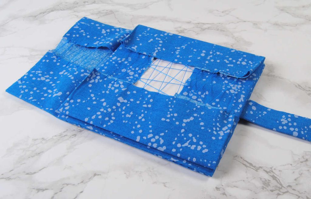 Layering a third fabric-covered square on top of the previous.