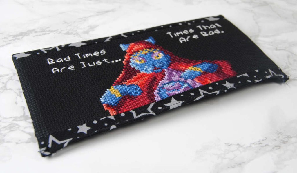 A fabric switch dock cover with a cross stitch panel.