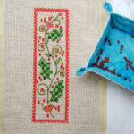 A finished cross stitch project embellished with seed beads.