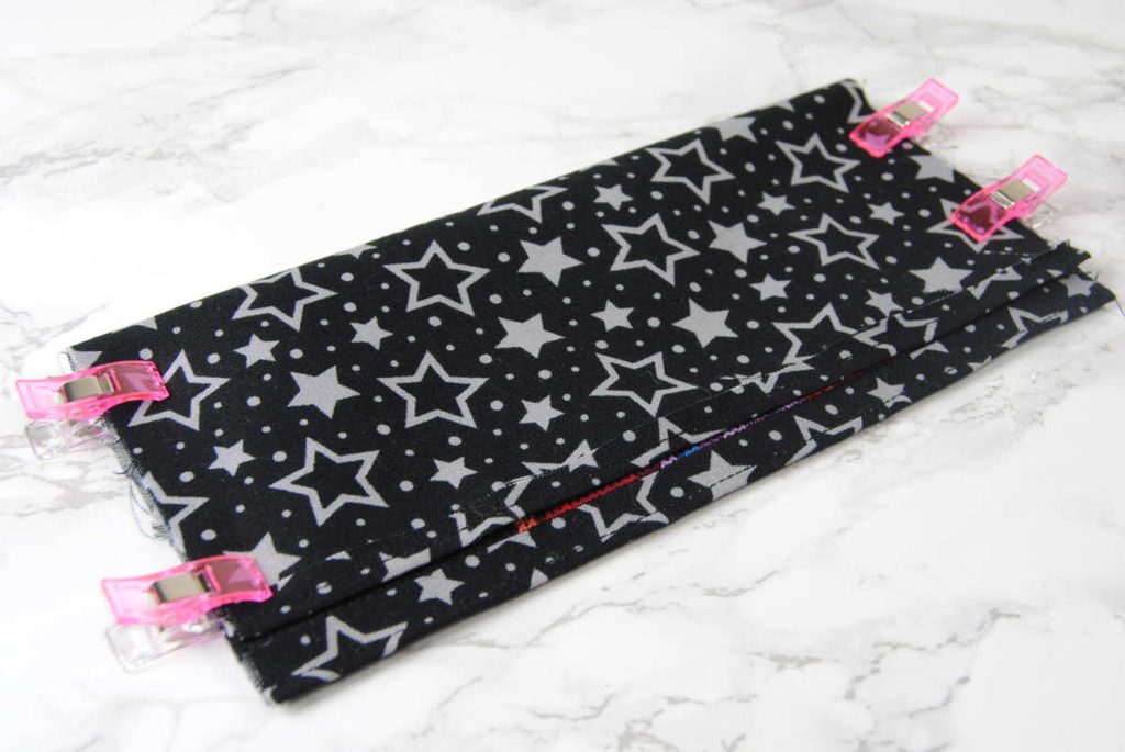 Folding fabric and clipping in place to prepare for sewing.