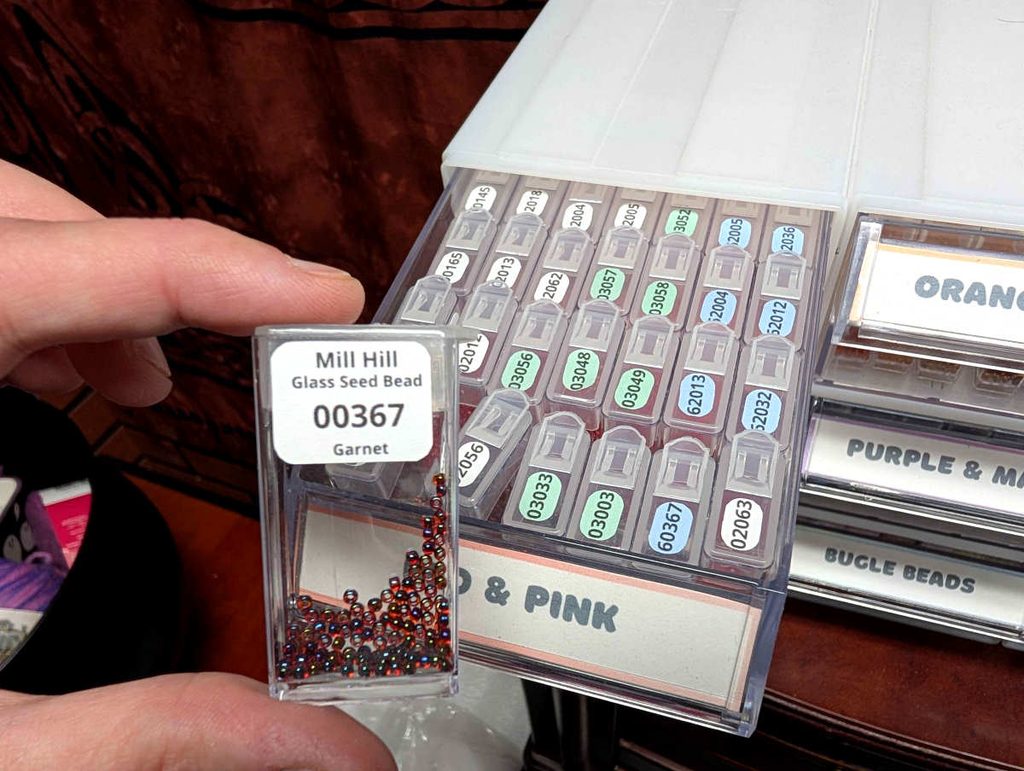 Example of a small labeled plastic tic-tac style container full of seed beads.