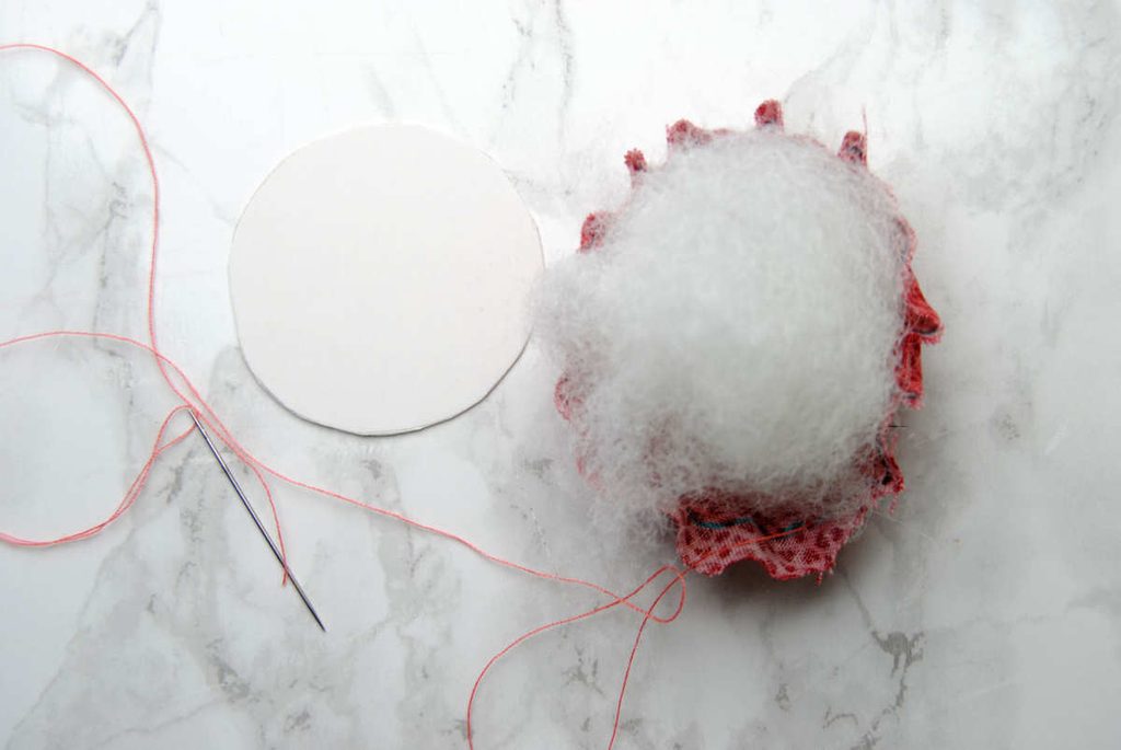 Adding stuffing to the top of a pin drum to create the domed shape.