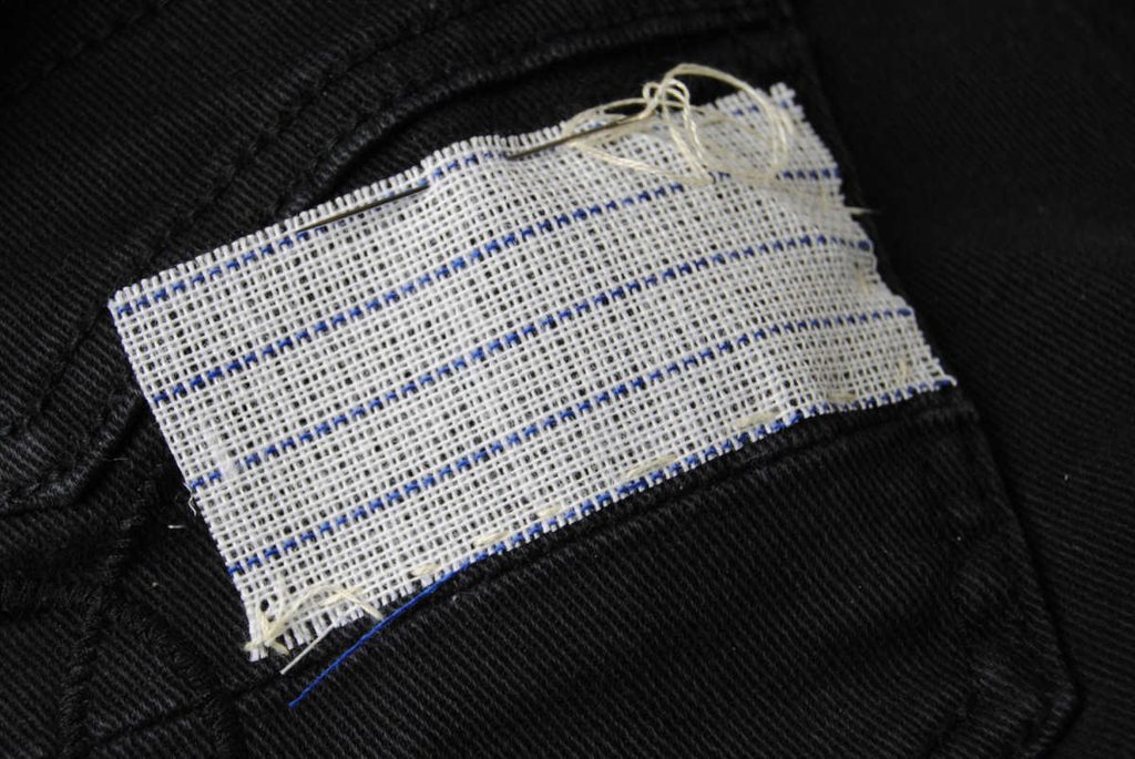 Demonstrating basting waste canvas onto your fabric.