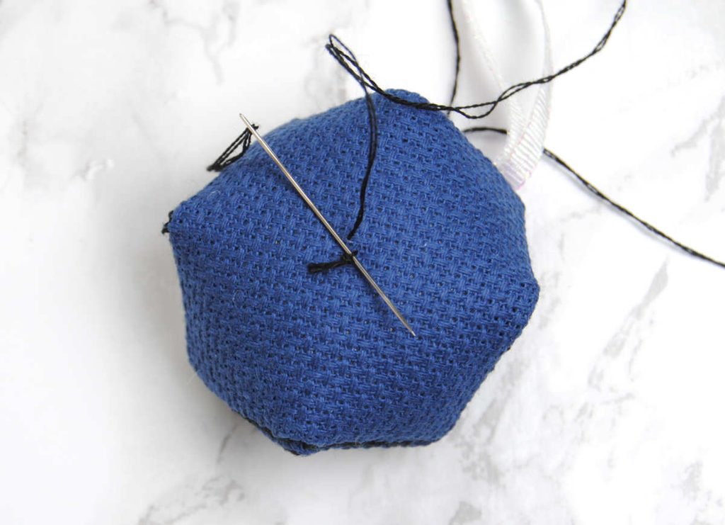 Demonstrating securing your thread before attaching a second button on the back.