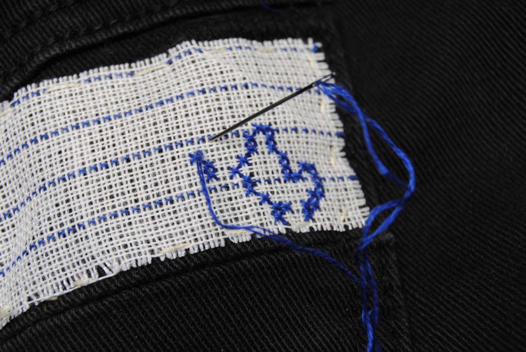 Starting to cross stitch onto basted waste canvas.
