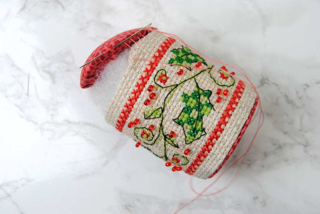 Demonstrating sewing the top of a pin drum on using a ladder stitch.