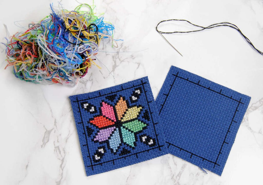 Materials for a biscornu; two precut squares of aida, needle and thread, and some stuffing.