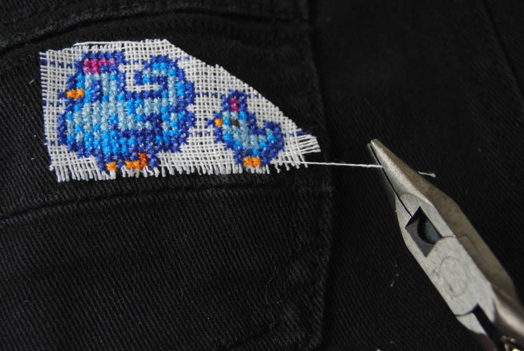 Starting to pull out waste canvas strands using needlenose pliers