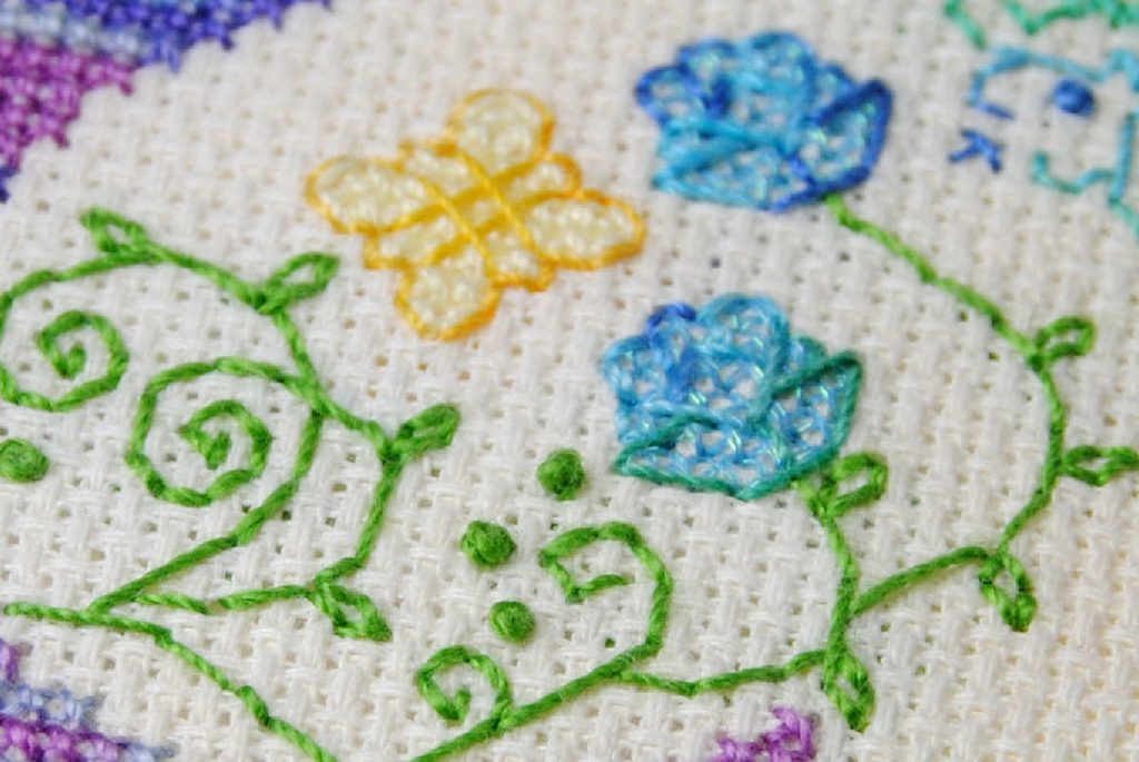 Close up of flowers and vines cross stitch and backstitched in Sulky brand thread.