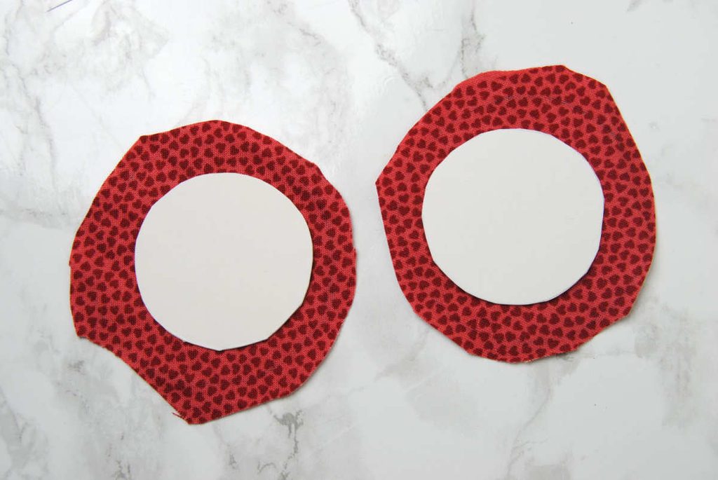 Fabric vaguely resembling circles cut larger than two cardstock circles.