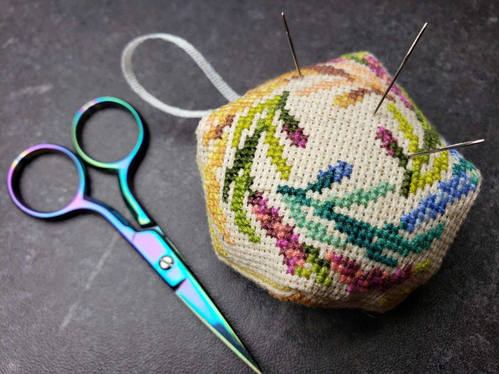 Closeup of a zelda-themed biscornu with no button. Scissors nearby for scale.