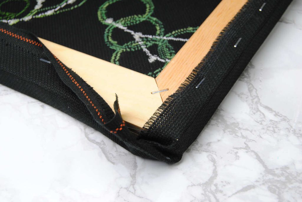 Turning and folding over the the corner of your stretched canvas.