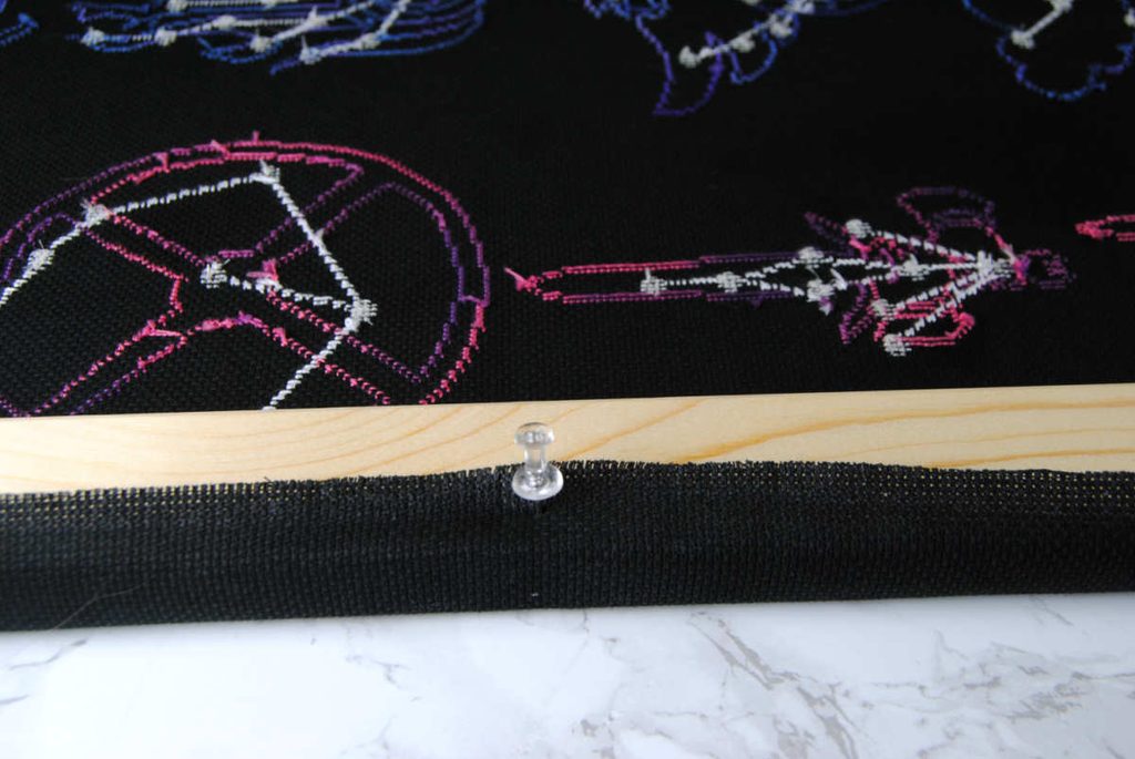 Using a pushpin to test out fabric placement before stapling it in place.