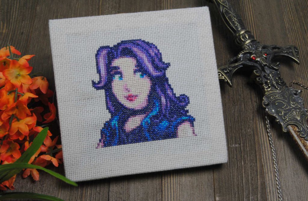A cross stitch stretched canvas square of Abigail from Stardew Valley.