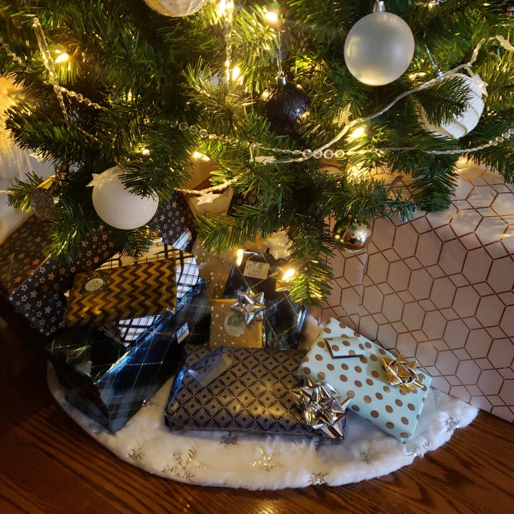 Shot of a pile of presents under a Christmas tree, all in combinations of black, white, and gold.