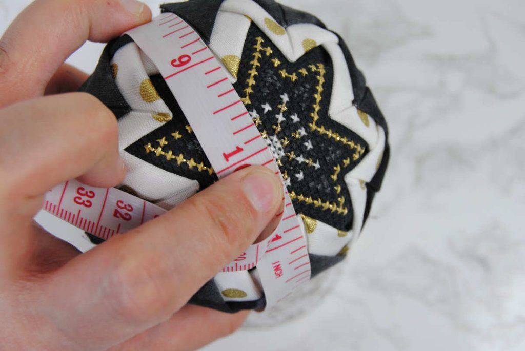 Using measuring tape to determine the center of your bauble and mark the center of the opposite side.