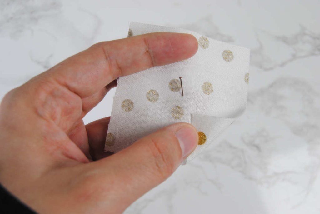 Place a pin in the center of a fabric square.