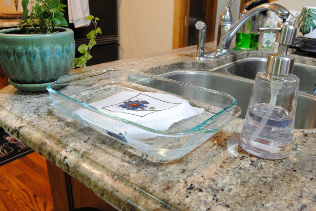 Washing a cross stitch project in lightly soapy water.