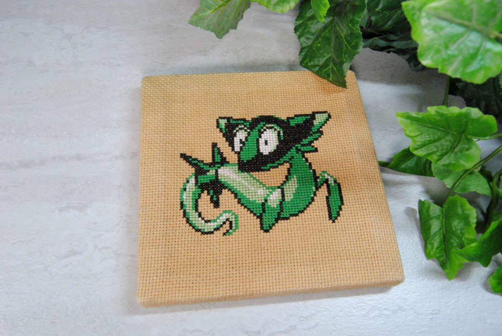 A cross stitch of Dreepy from Pokémon on tea dyed aida.